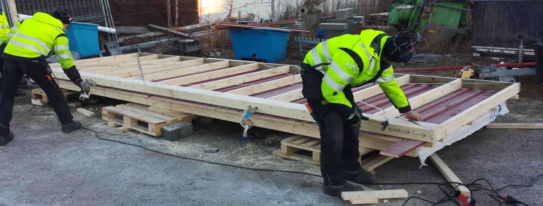 Snickare på byggföretaget umeå ab sågar och spikar när det håller på att förbreda väggmodul till en sopskjul som ska stå på gimonäs