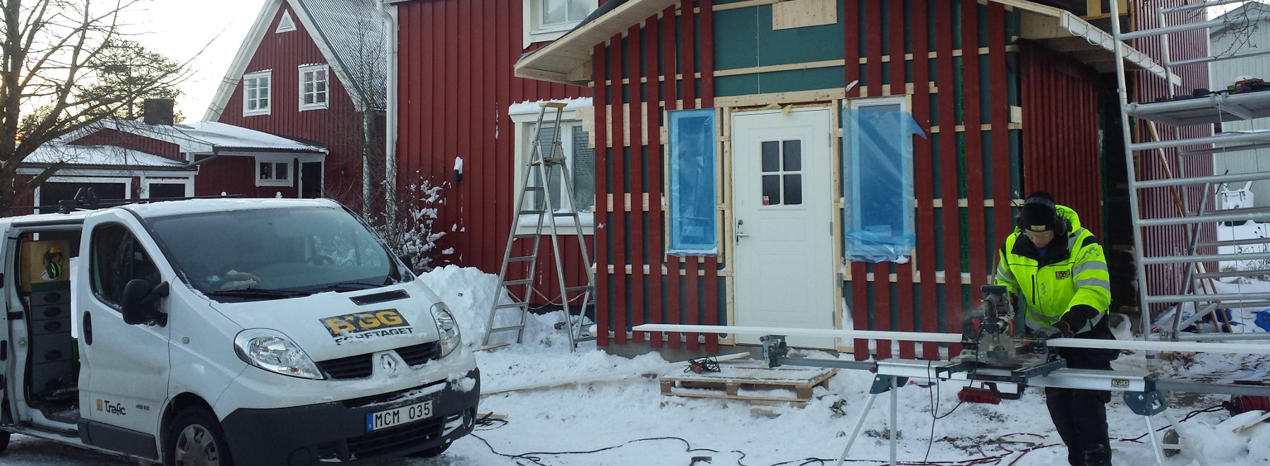Bilden visar ett arbete med en tillbyggnad av en hall till en vill. En snickare står och sågar brädor till väggarna.